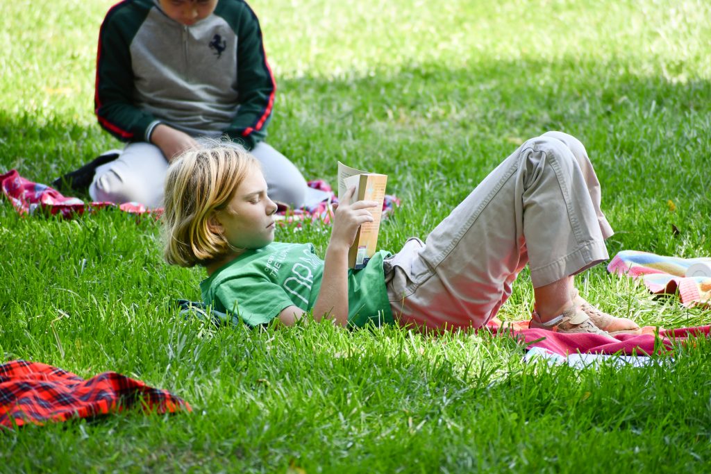 A student reads outdoors during a Lower School class.