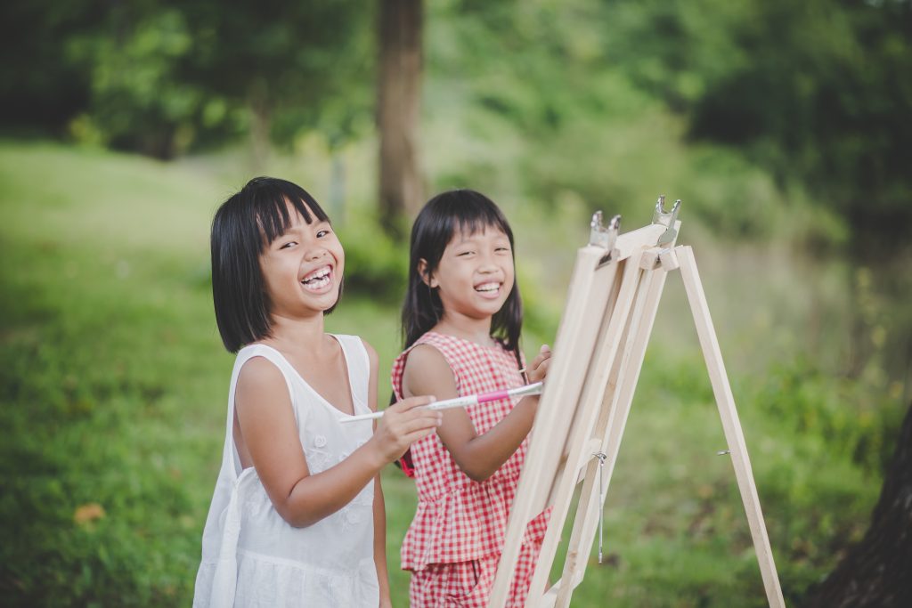 Two little girl painter art drawing in the park.