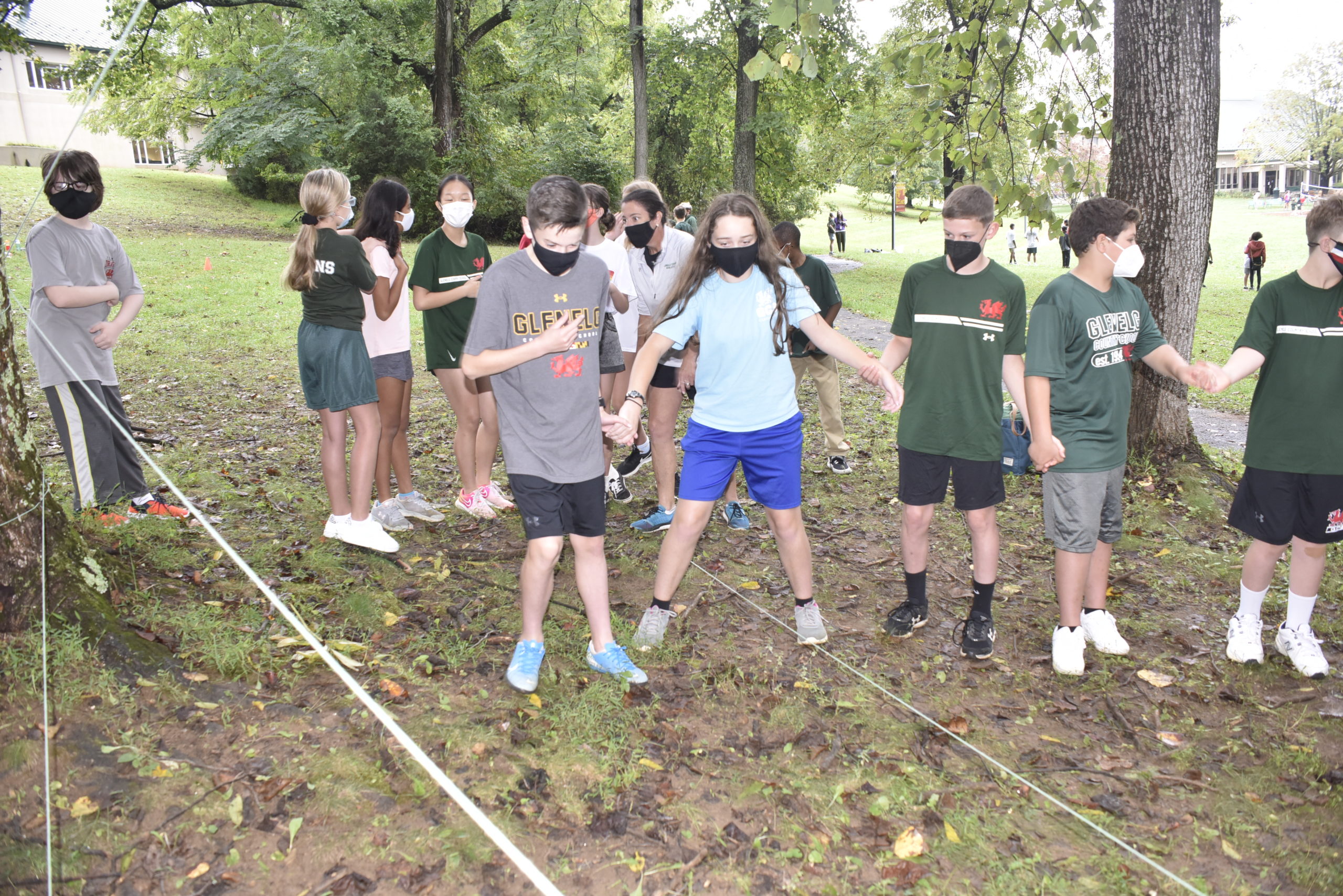 Middle School students attempt to conquer a ropes obstacle course in the woods.