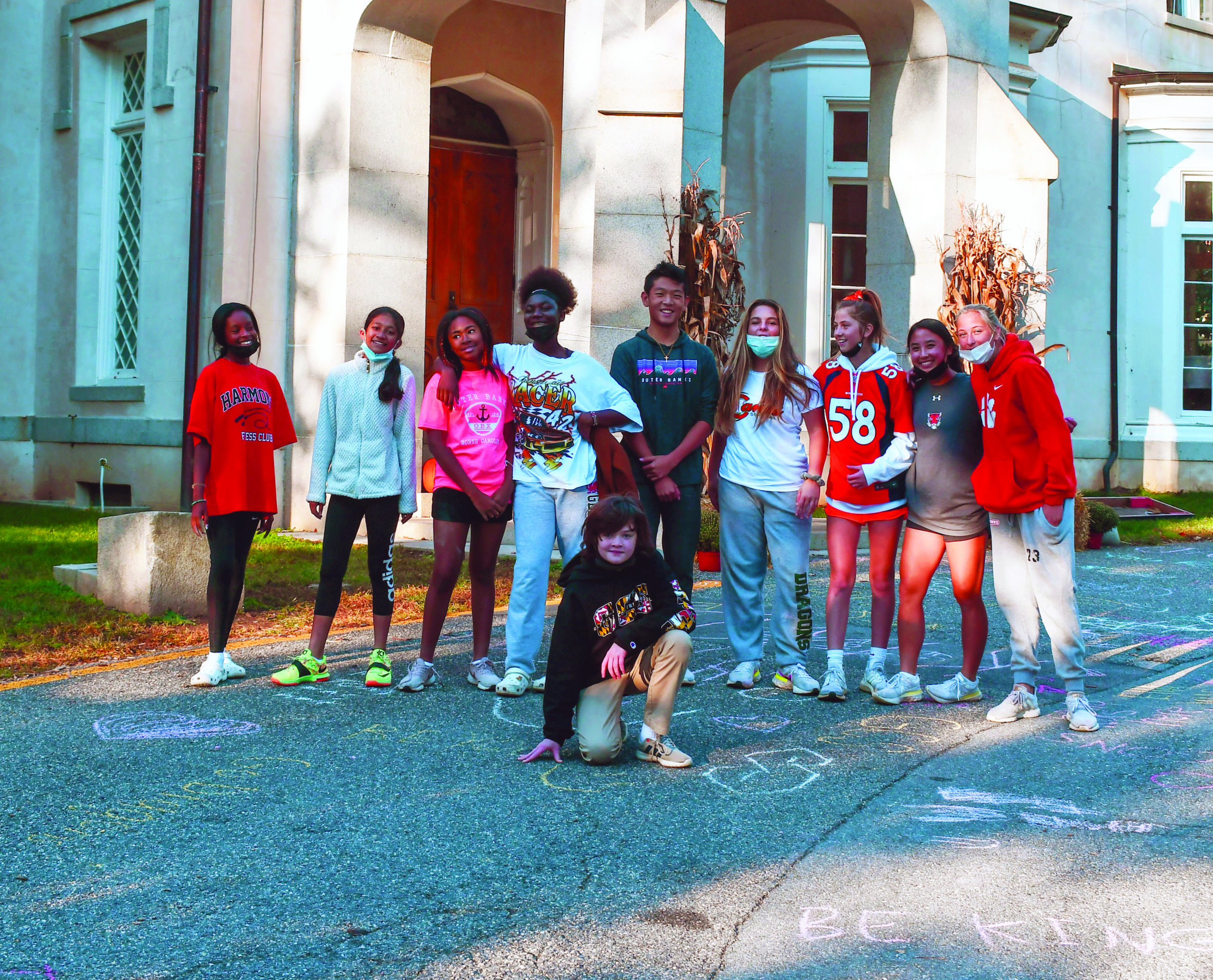 Middle School students pose in front of the Manor House after writing messages of affirmation in chalk.