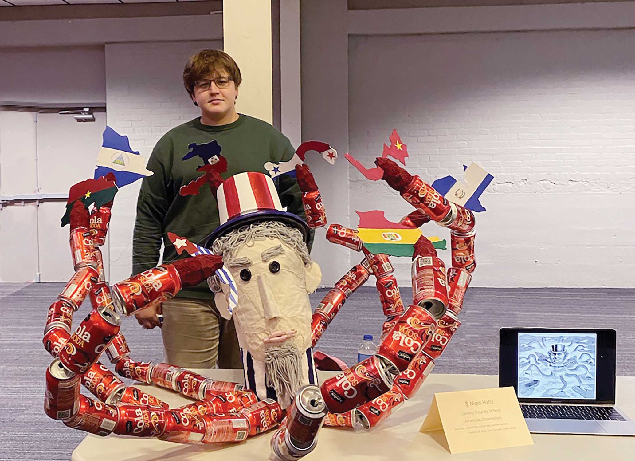 Nigel Hafiz '23 stands behind his recycled art project.