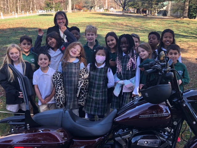 Students gather behind a motorcycle during a lesson about school readiness.