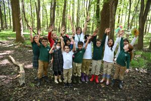 A group of students and their teacher raise their arms overhead in excitement.