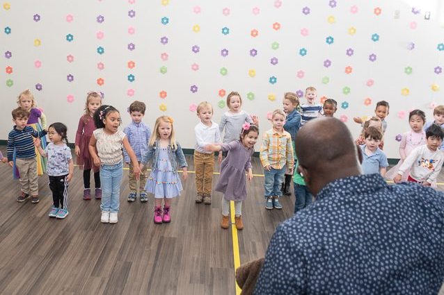 preschool class performing a song in front of music teacher and audience.