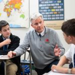 A teacher assists two students.