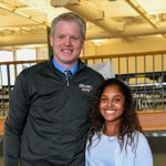 A teacher and alumnus stand together.