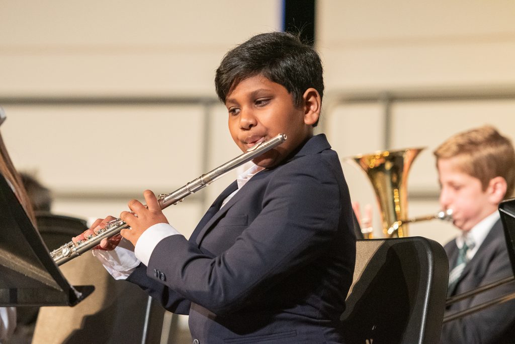 An elementary school child plays the flute.