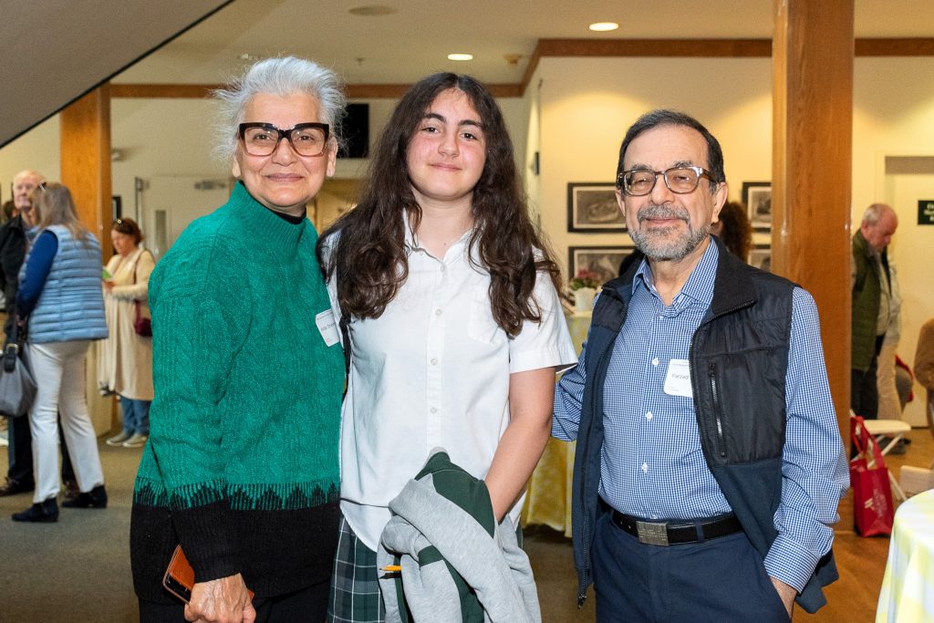 A middle school girl poses for a photo with her grandparents.