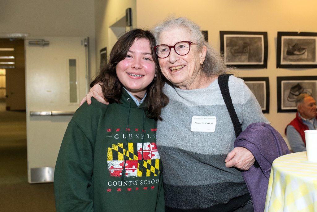 A grandmother puts her arm around her middle school granddaughter as they pose for a photo.
