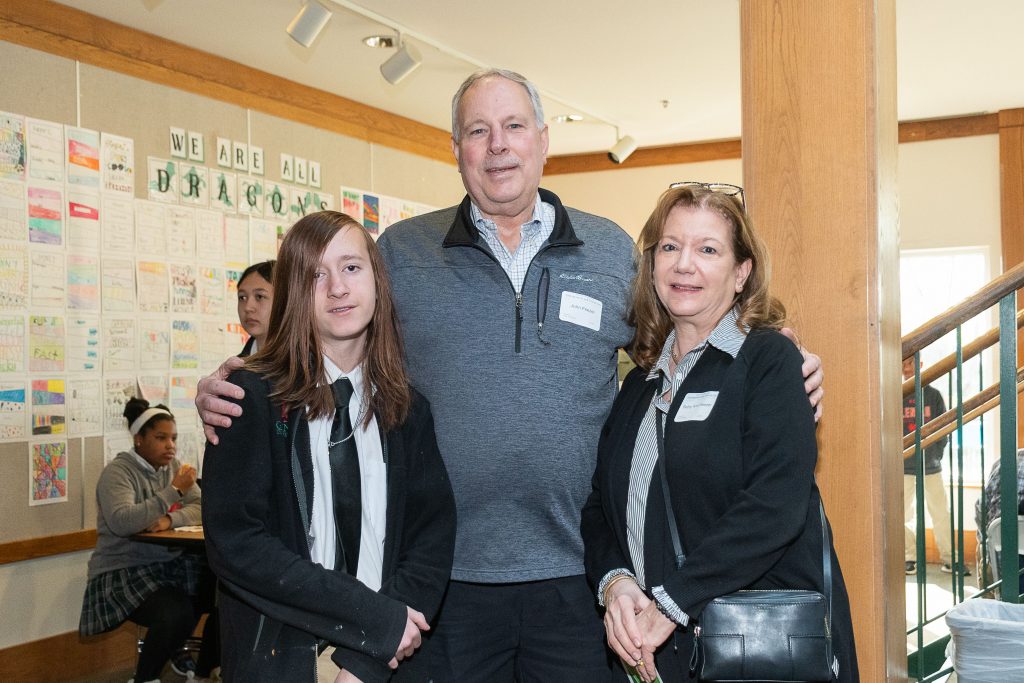 grandparents pose with the their middle school grandchild.