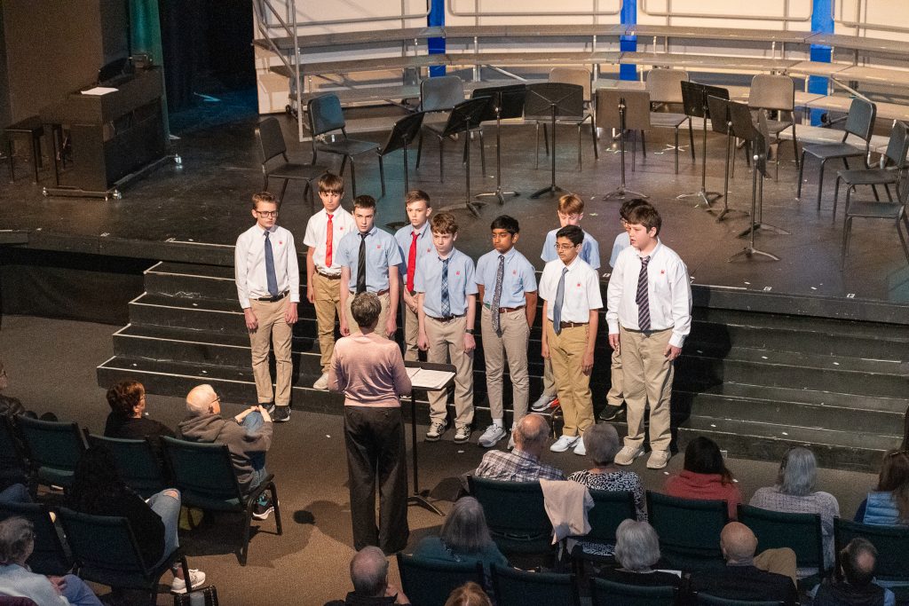 A group of middle school boys perform onstage for audience.