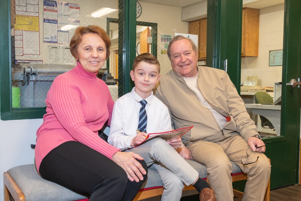 Grandparents sit on a bench with their grandson