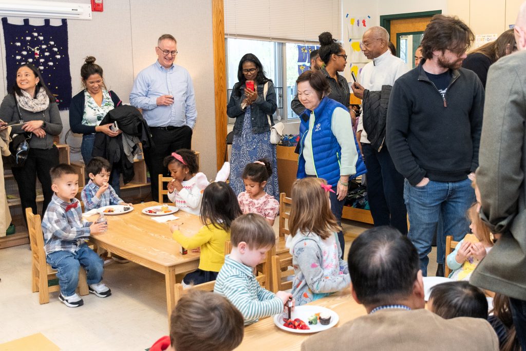 Grandparents in a classroom look on as their grandchildren enjoy snacktime.
