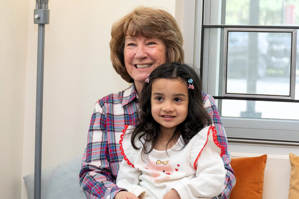 A grandchild sits on her grandmother's lap.